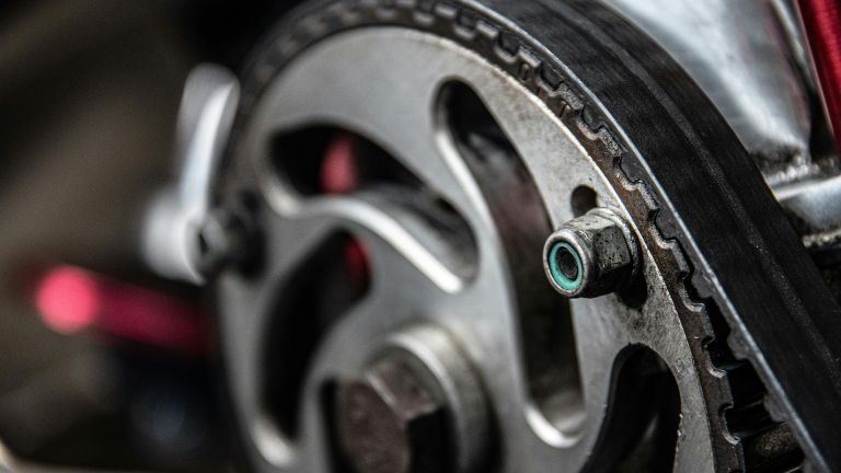Close-up of a metallic gear and rubber belt in an engine, showcasing intricate details, textures, and industrial precision, with a focused, mechanical tone.